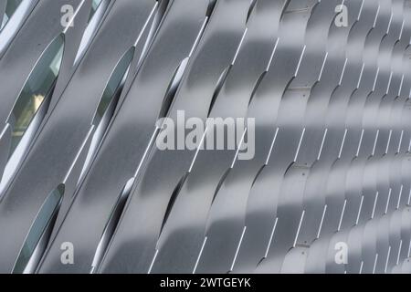 Nahaufnahme von silbergrauen, abgewinkelten äußeren Aluminiumluken über einem Gebäude Fenster - Verglasung. Stockfoto