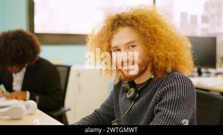 Ein moderner Mann lächelt während er im Coworking Space arbeitet Stockfoto