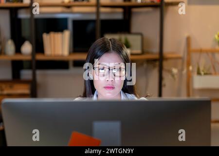 Die junge Frau sitzt und starrt auf den Computerbildschirm Stockfoto