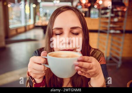 Ein ruhiger Morgen, als eine junge Frau in einem gemütlichen Urban Coffee Shop Kaffee trinkt. Stockfoto