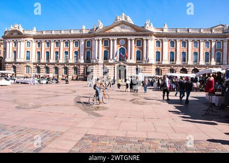 Toulouse Haute Garonne France 03.13.24 Place du Capitole. Großes großes Rathaus aus großen Steinen und roten Backsteinen. Fenster und Balkone. Flaggen, Statuen. Fußgänger Stockfoto