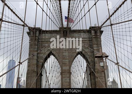 Brooklyn Bridge, Nahaufnahme eines Brückenturms mit schwenkender Flagge, umwickelt in Seile und Kabel, Manhattan, New York City, New York, USA, Nordamerika Stockfoto