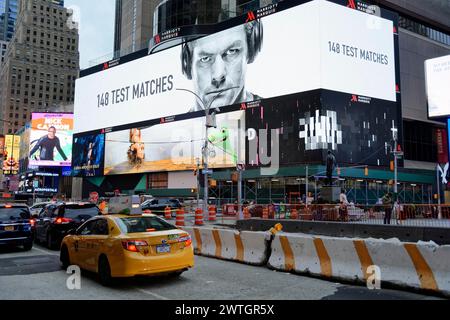 Ein gelbes Taxi fährt an einer mit Werbeplakaten geschmückten Baustelle vorbei, Manhattan, New York City, New York, USA, Nordamerika Stockfoto