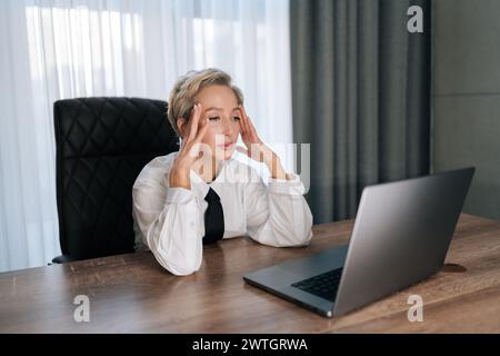 Ermüdete stressige Unternehmerin 50er Jahre, die schlechte Nachrichten im Laptop liest. Traurig besorgt, Geschäftsfrau mittleren Alters, die denkt, Problemlösung Sorge zu tragen Stockfoto