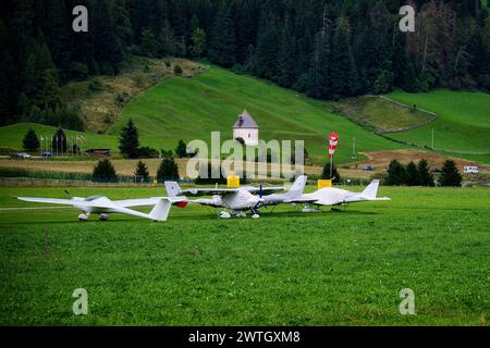 Die drei kleinen Flugzeuge parkten auf einem Feld mit einer Scheune im Hintergrund. Stockfoto