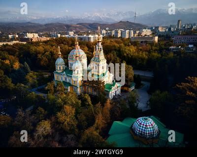 Luftdrohnen-Panorama der Ascension Cathedral Russisch-orthodoxe Kirche und Schneeberge im Hintergrund im Panfilov Park vor Sonnenuntergang Himmel in Almat Stockfoto