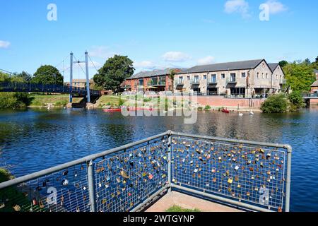 Blick auf die Cricklepit-Hängebrücke über den Fluss exe mit Lovelocks auf Geländern im Vordergrund und Restaurant am Kai hinten, Exeter, Großbritannien. Stockfoto