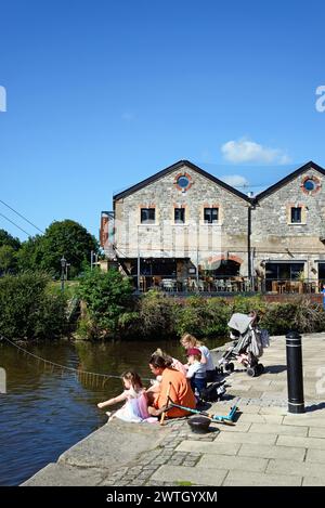 Familie, die am östlichen Kai des Flusses exe sitzt, mit einem Restaurant auf der Rückseite, Exeter, Devon, Großbritannien, Europa. Stockfoto