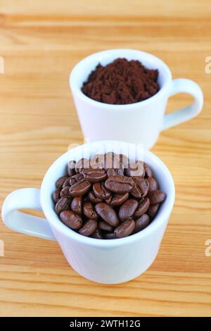 Nahaufnahme einer Tasse gerösteter Kaffeebohnen mit einer Tasse verschwommenem gemahlenem Kaffee Stockfoto