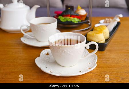 Zwei Tassen heißer Tee mit verschwommenen Scones und Gebäck am Nachmittag Stockfoto