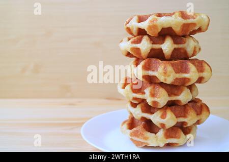 Teller mit leckeren belgischen Waffeln auf Holztisch Stockfoto