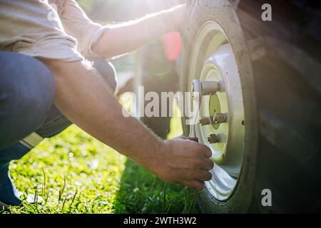 Landwirt, der das Rad am Traktor befestigt. Ernte von Feldfrüchten, Sammeln von Gemüse auf Familienbetrieb. Konzept der Landwirtschaft, der landwirtschaftlichen Wirtschaft. Stockfoto