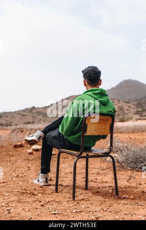 Ein junger Mann sitzt auf einem Stuhl auf einem Berg in Marokko. Stockfoto