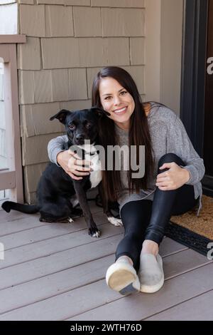 Die strahlende Frau und ihr treuer Hund genießen einen entspannten Moment auf der Veranda Stockfoto