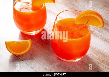Orangengetränke auf hölzernem Hintergrund, frisch gepresster Saft mit Fruchtscheiben auf einem rustikalen Tisch Stockfoto