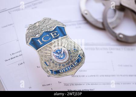 KIEW, UKRAINE - 9. MÄRZ 2024 US ICE Officer Badge mit Handschellen auf vielen Durchsuchungsbefehlen und Beschwerden des US District Court Nahaufnahme Stockfoto