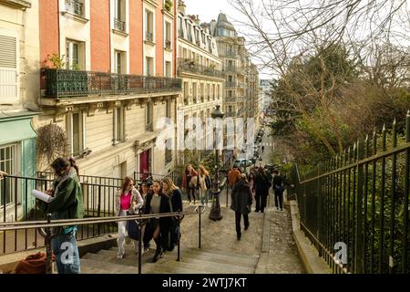Paris, Frankreich - 17. Februar 2024 : Blick auf Touristen, die die malerischen Treppen mit den Laternen im Montmartre-Viertel in Paris hinauf und hinuntergehen Stockfoto