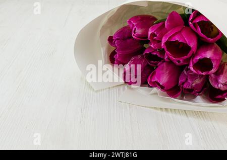 Nahaufnahme von Tulpen in leerer Papiertüte auf Holztisch Stockfoto
