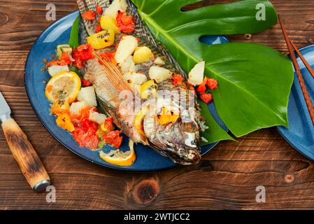 Gebratener Tilapia-Fisch mit Zitrussoße auf Blatthintergrund. Stockfoto