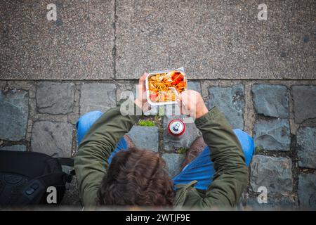 Konzept, Blick von oben auf einen Touristen, der auf der Straße auf dem Camden Market in London chinesisches Essen isst Stockfoto