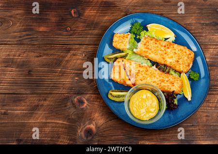 In Semmelbröseln gebratenes Pollock-Filet mit Soße und Kiwi. Fisch in Chips. Stockfoto