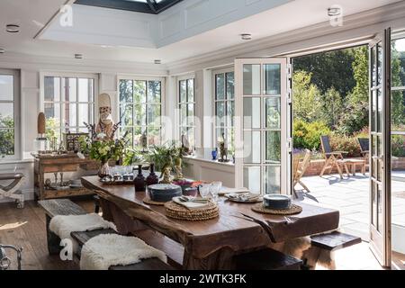 Holztisch. Mit offenen Türen vom Wintergarten bis zur Terrasse des irischen Hauses in Greystones, County Wicklow, Irland Stockfoto