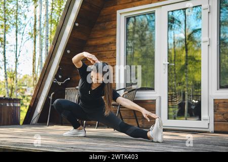 Sportliche Frau, die seitliche Pisten auf der Terrasse des Bungalows macht Stockfoto