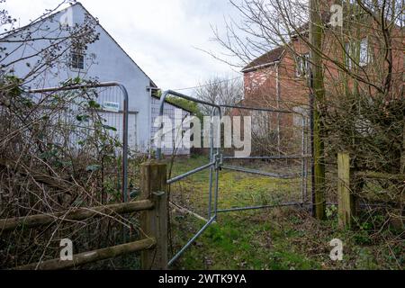 Ein leeres und verschlossenes Haus wartet auf den Abriss, mit einem hohen Drahtzaun, der jeden abhält, der sich dem Ort nähert. Stockfoto