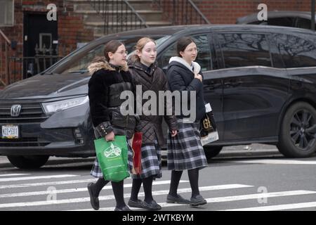 Orthodoxe jüdische Klassenkameraden, die dieselben Schottenröcke tragen, überqueren eine Straße in Brooklyn, New York. Stockfoto