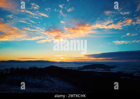 Sonnenuntergang in den Bergen. Die Sonne taucht hinter Berggipfeln mit goldenem Licht. Wunderschöne Naturlandschaft Stockfoto