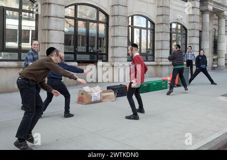 Yeshiva-Schüler und -Mitschüler spielen ein mysteriöses Spiel von Lauf und Tag. Auf den Straßen von Brooklyn an einem warmen Wintertag im Jahr 2024. Stockfoto