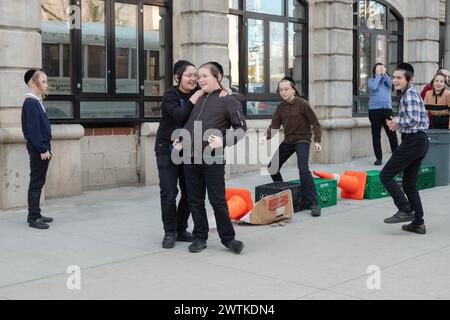 Yeshiva-Schüler und -Mitschüler spielen ein mysteriöses Spiel von Lauf und Tag. Auf den Straßen von Brooklyn an einem warmen Wintertag im Jahr 2024. Stockfoto