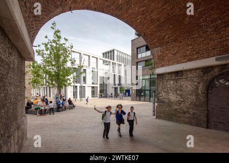 Blick über die Fußgängerzone vor der St. Marys Schule durch die Eisenbahnbögen. Battersea Exchange und St. Mary's RC Primary School, London, Stockfoto