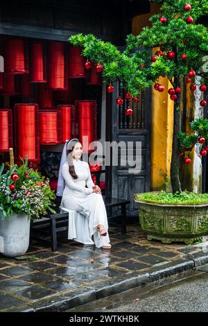 Hoi an, Vietnam, 21. November 2022: Eine junge Frau im Brautkleid posiert für ein Foto vor einem traditionellen vietnamesischen Geschäft in Hoi an, Vietnam Stockfoto