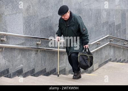 Mann mit Gehstock, der Treppen auf der Stadtstraße klettert Stockfoto