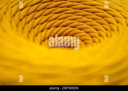 Knäuel aus gelber geflochtener synthetischer Schnur, Nahaufnahme, selektiver Fokus, abstrakter Hintergrund der Textilindustrie Stockfoto