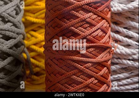 Verschiedene Knäuel aus mehrfarbigem geflochtenem synthetischem Band, abstrakter Textilindustrie-Hintergrund Stockfoto