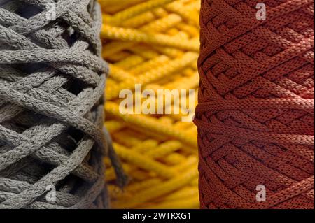 Verschiedene Knäuel aus mehrfarbigem geflochtenem synthetischem Band, abstrakter Textilindustrie-Hintergrund Stockfoto