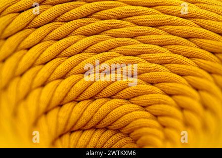 Knäuel aus gelber geflochtener synthetischer Schnur, Nahaufnahme, selektiver Fokus, abstrakter Hintergrund der Textilindustrie Stockfoto