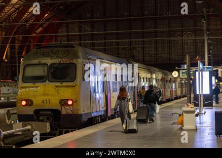 Antwerpen, Belgien, 25. Januar 2024, wenn der Abend abfällt, Passagiere werden am Hauptbahnhof von Antwerpen in einen mit Graffiti geschmückten Zug einsteigen sehen. Das Vorhandensein von Graffiti deutet auf eine Erzählung städtischer Ausdrucksformen innerhalb des öffentlichen Verkehrssystems hin. Pendler mit Gepäck gehen entlang der Bahnsteige und bereiten sich auf ihre Reise vor, während sich die historische Eisenwerkstruktur des Bahnhofs darüber erhebt und der Szene ein Gefühl zeitloser Reise verleiht. Abendliches Boarding im Antwerpener Hauptbahnhof. Hochwertige Fotos Stockfoto