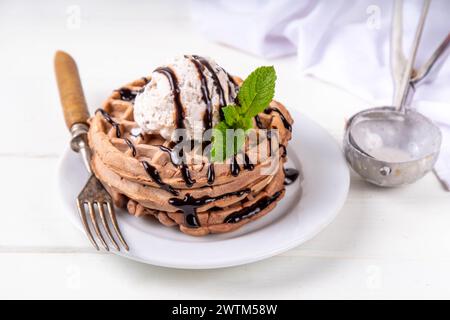Stapel belgischer Schokoladenwaffeln mit Eis und schokoladenbelag. Frühstückswaffeln mit Eis, Schokoladensoße und Pfefferminze Stockfoto