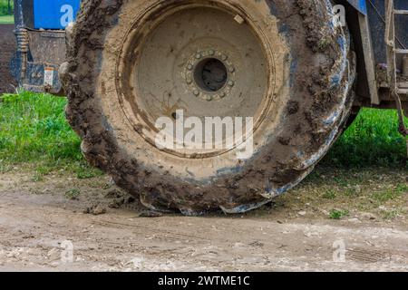 Schmutziges Doppelrad eines großen landwirtschaftlichen Traktors auf unbefestigter Straße am Sommertag Stockfoto