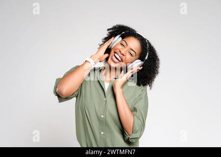 Eine lebendige afroamerikanische Dame wird während des Tanzes mit ihrem Smartphone in der Hand festgehalten, genießt ihre Lieblingslieder und zeigt einen Moment unbeschwerter Freude und musikalischer Wertschätzung. Stockfoto