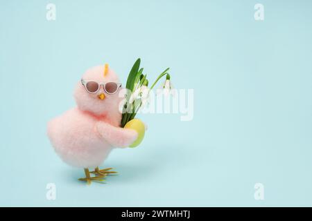 Kleine coole Küken in Sonnenbrille mit Osterei und Blumen auf blauem Hintergrund, Kopierraum Stockfoto