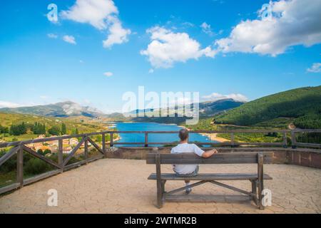 Mann sitzt auf der Bank am Aussichtspunkt über Camporredondo Behälter. Alba de los Cardaños, Palencia Provinz Castilla Leon, Spanien. Stockfoto