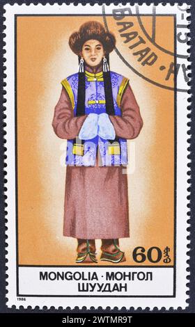 Von der Mongolei gedruckte Briefmarke, die Nationalkostüm zeigt, um 1986. Stockfoto