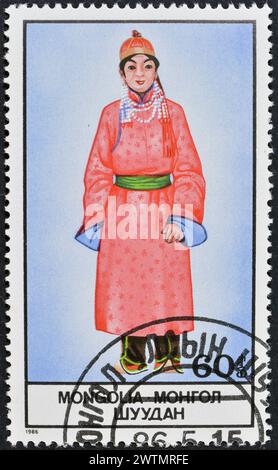 Von der Mongolei gedruckte Briefmarke, die Nationalkostüm zeigt, um 1986. Stockfoto