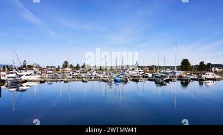 Blick auf die kleinen Motorboote und Segelschiffe, die an einem hellen Frühlingstag in der Deep Bay Marina, Vancouver Island, BC, vor Anker gebracht werden. Stockfoto