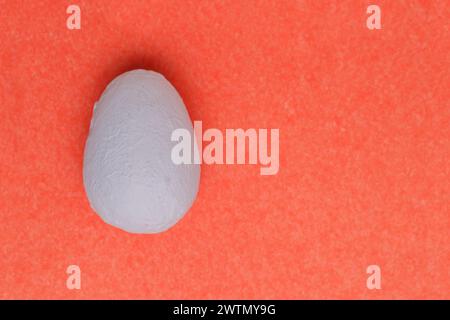 Makroflachung in Nahaufnahme, mit Textur. Dekoratives, handgemaltes hellblaues Ei auf rosafarbenem Papierhintergrund. Stockfoto