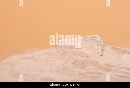 Strandsand mit Kopierraum und grauem Betonsteinpodium für Kosmetik oder Produkte. Auf beigefarbenem Hintergrund Stockfoto